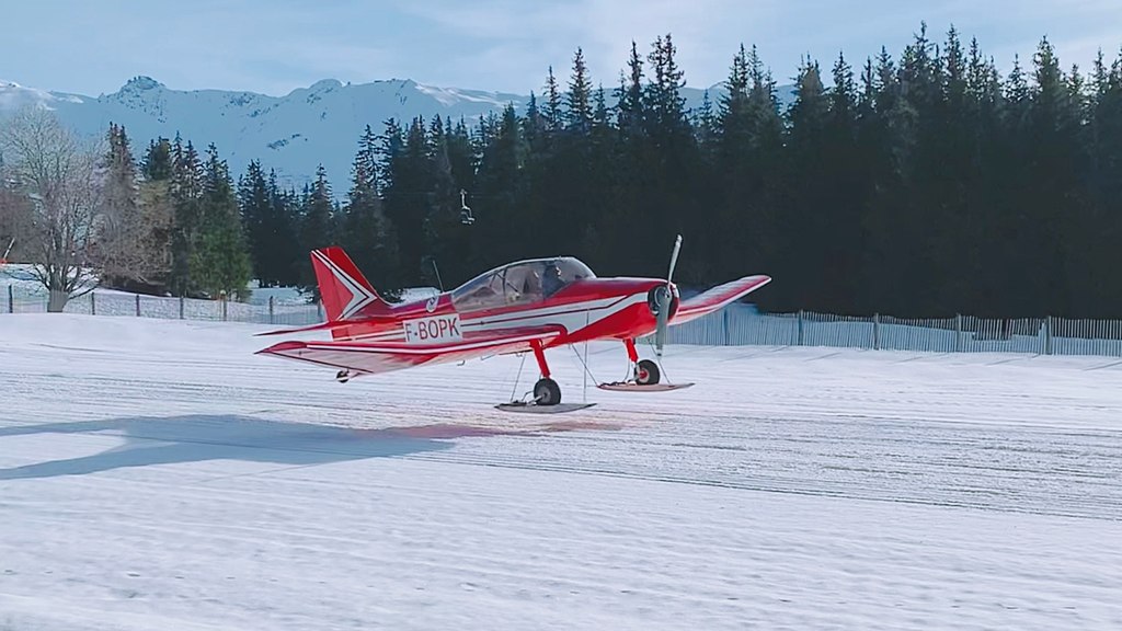 Jodel D140R skis attached to its landing gear. Taking - off from Meribel airport the runway is cover with snow